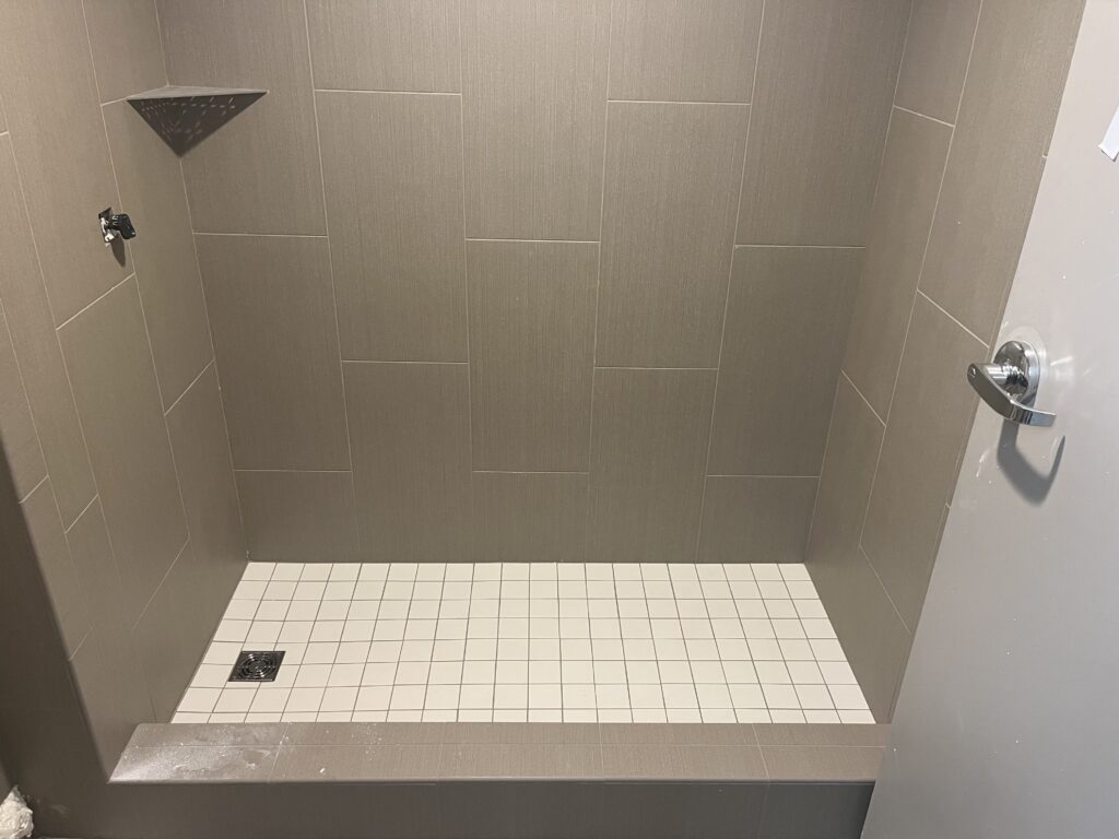 This image features a walk-in shower with grey tiling